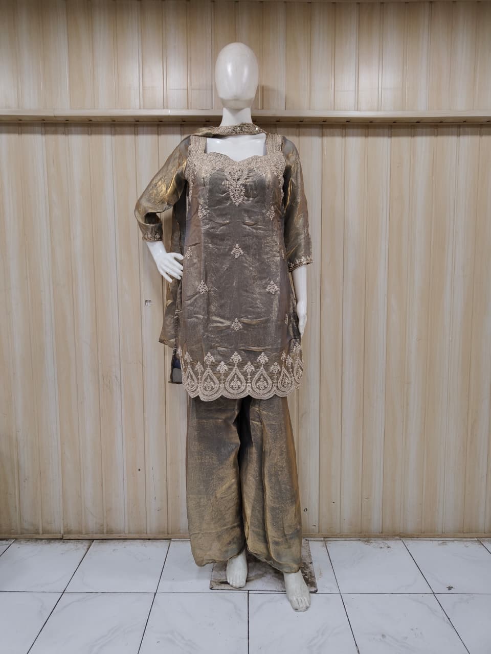 beige embroidered outfit on mannequin against striped