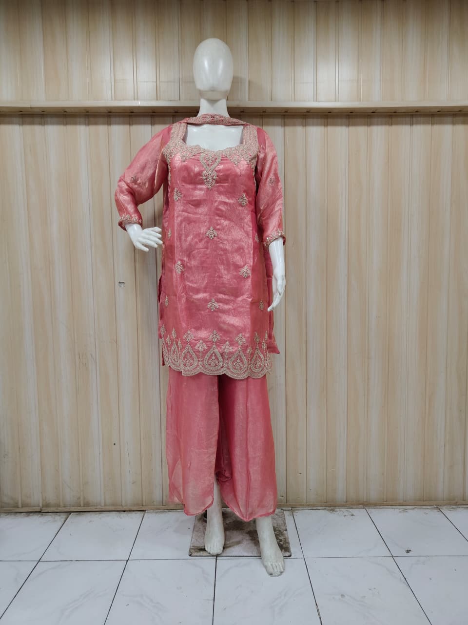 pink embroidered outfit on mannequin against striped