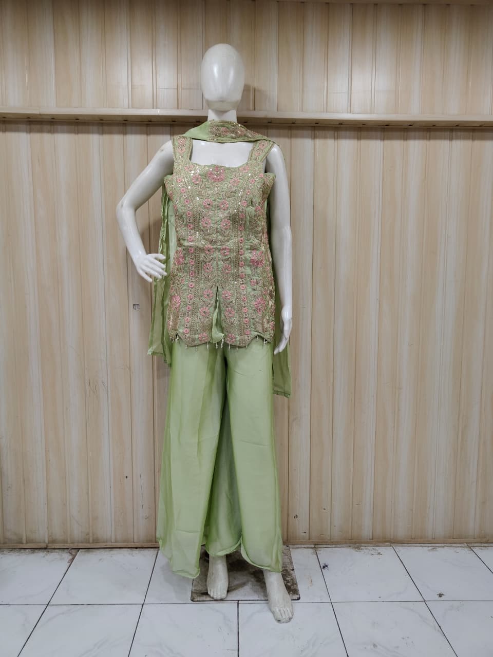 green embroidered outfit on mannequin against striped