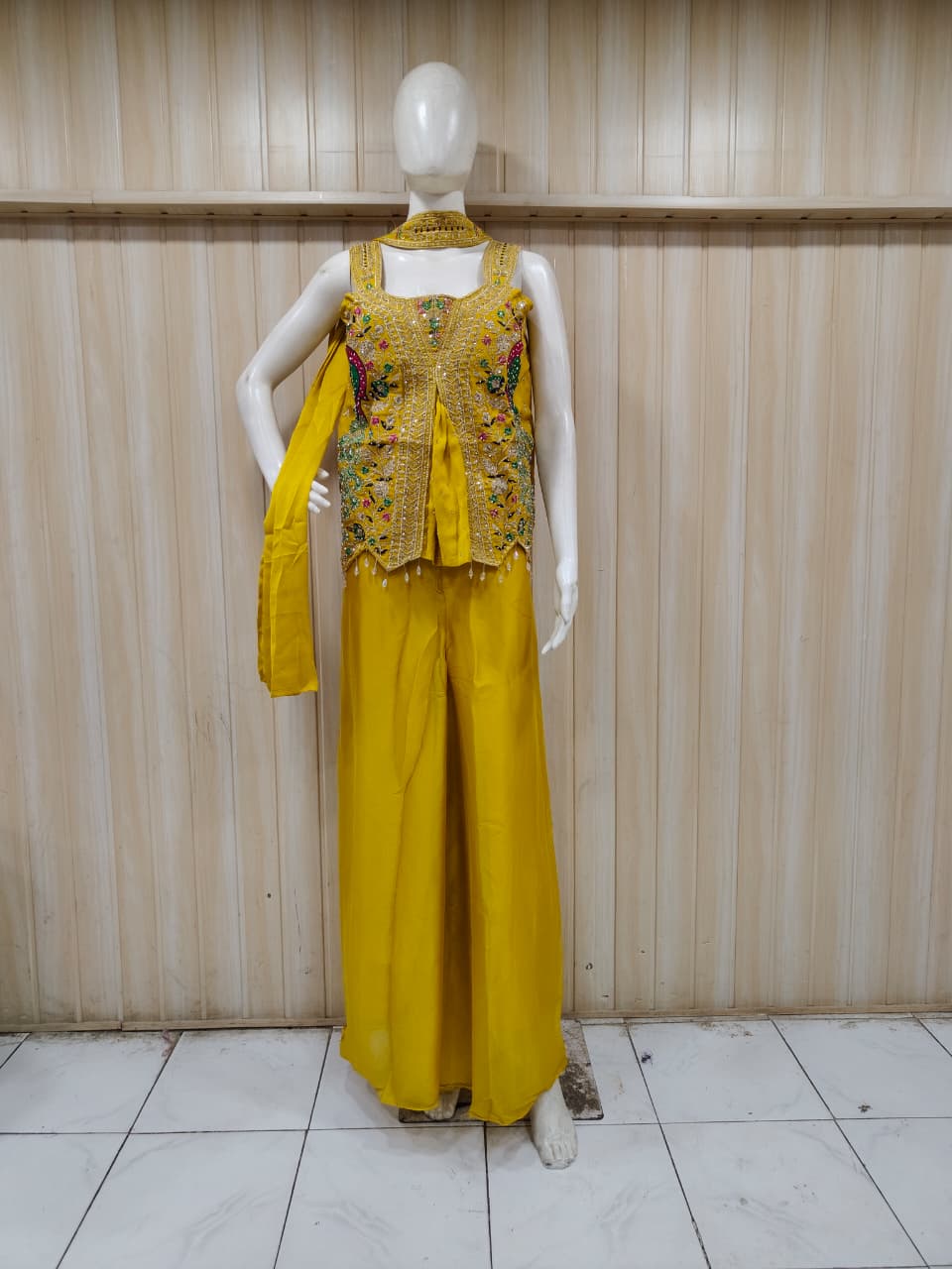 yellow embroidered outfit on mannequin against striped