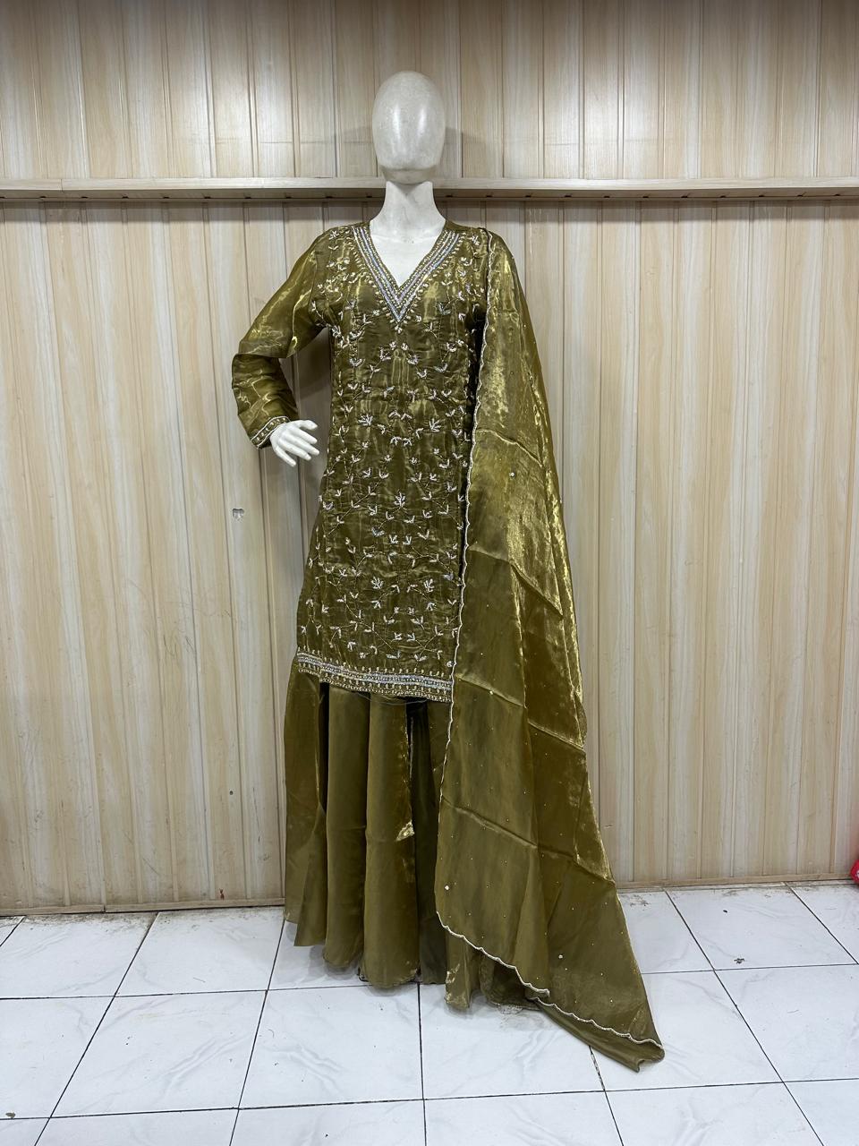 Green embroidered traditional outfit on a mannequin against a striped