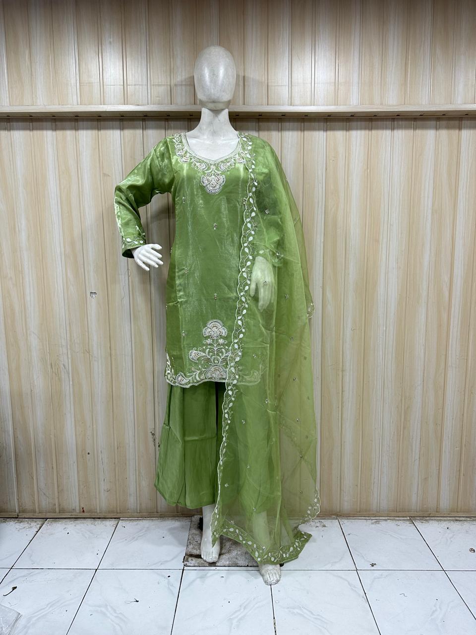 Green embroidered outfit on a mannequin against a striped