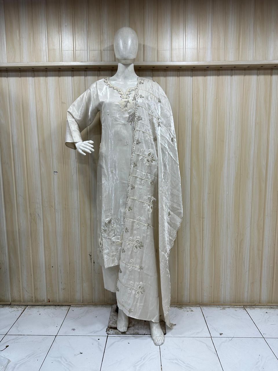white traditional outfit with matching dupatta on a mannequin against a striped