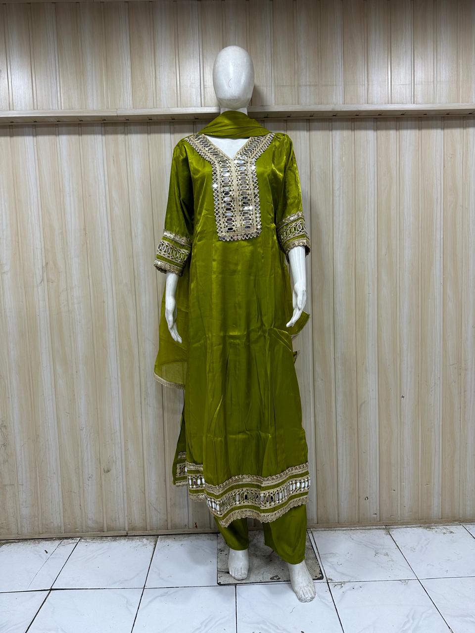 Elegant green traditional outfit with matching dupatta on mannequin against striped background – perfect for a fresh, graceful & classy ethnic look