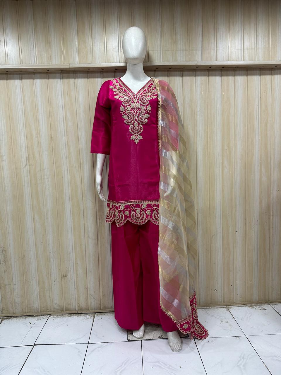 dark pink traditional outfit with matching dupatta on a mannequin against a striped