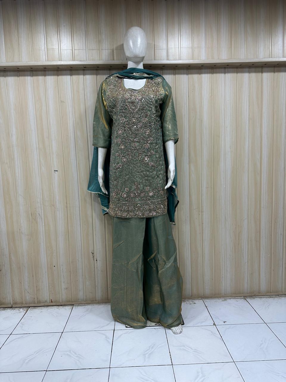 green traditional outfit with matching dupatta on a mannequin against a striped