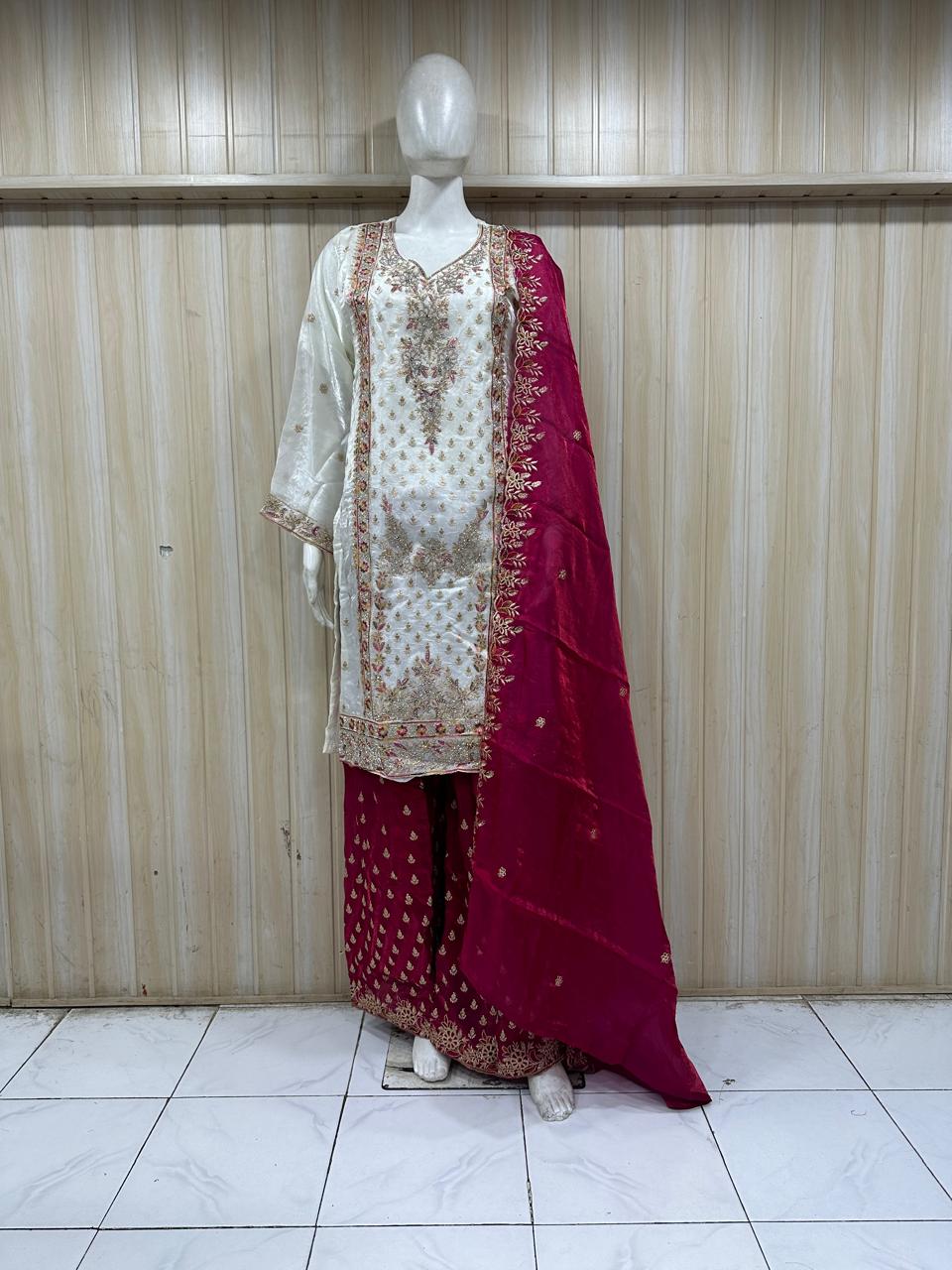 white and red traditional outfit with matching dupatta on a mannequin against a striped