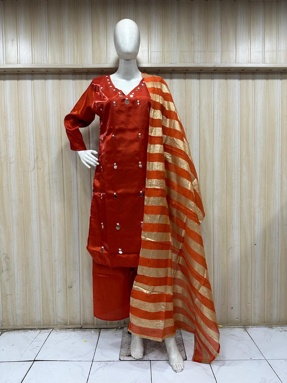 orange traditional outfit with matching dupatta on a mannequin against a striped