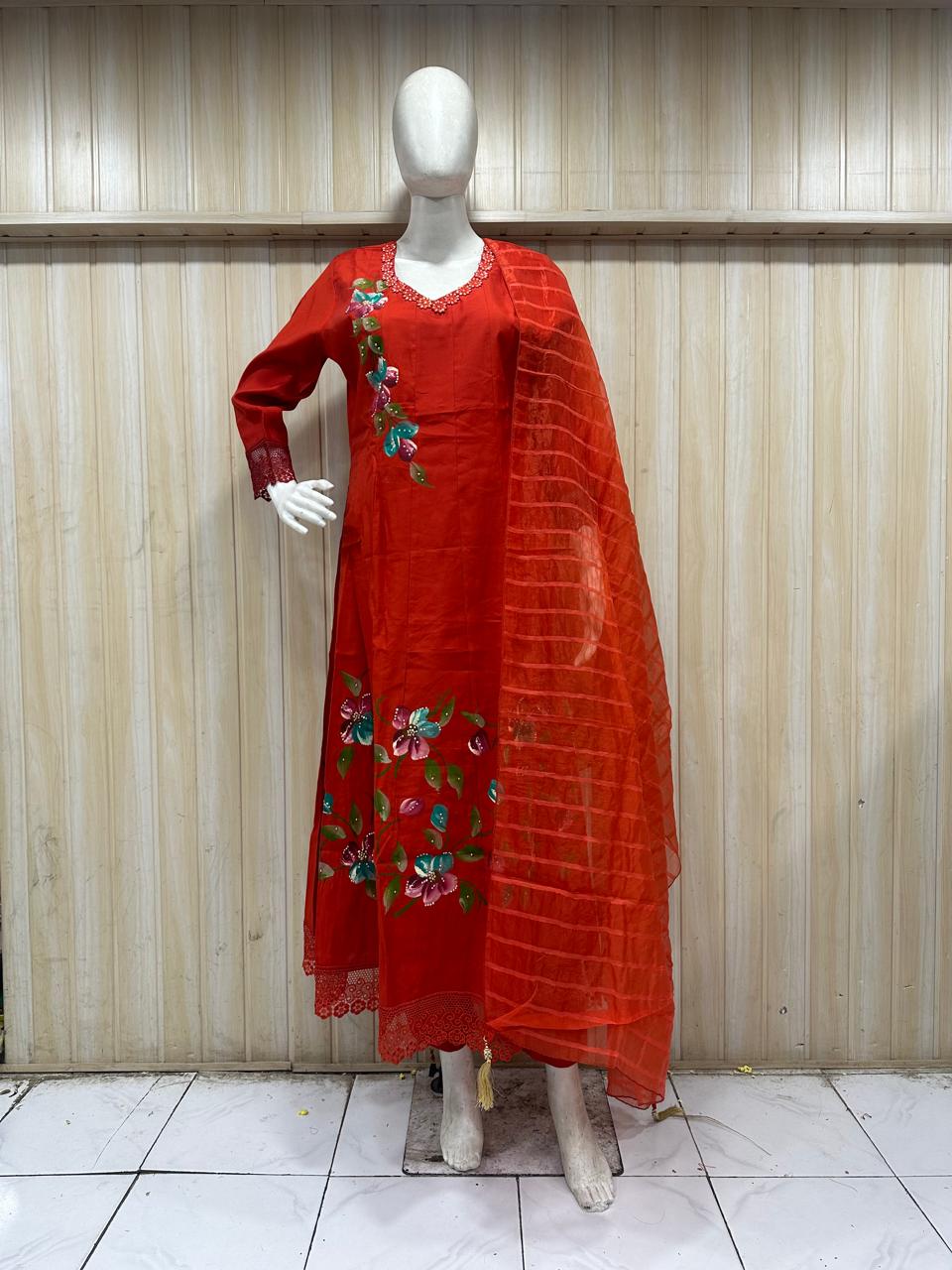 orange traditional outfit with matching dupatta on a mannequin against a striped