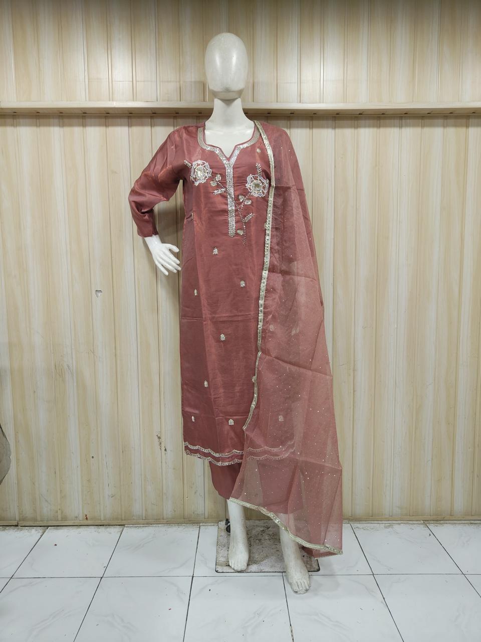 rose gold traditional outfit with matching dupatta on a mannequin against a striped