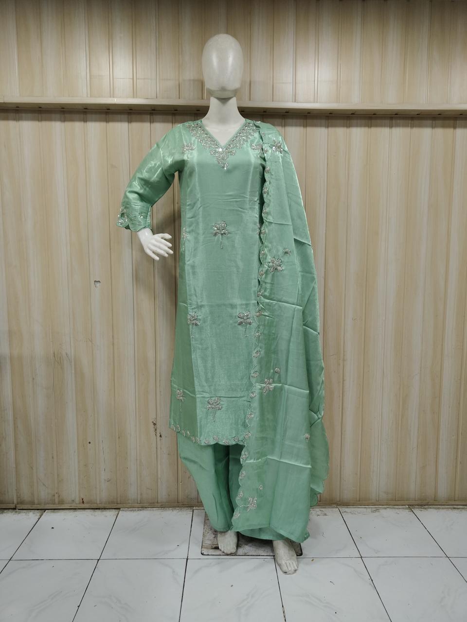 green gold traditional outfit with matching dupatta on a mannequin against a striped