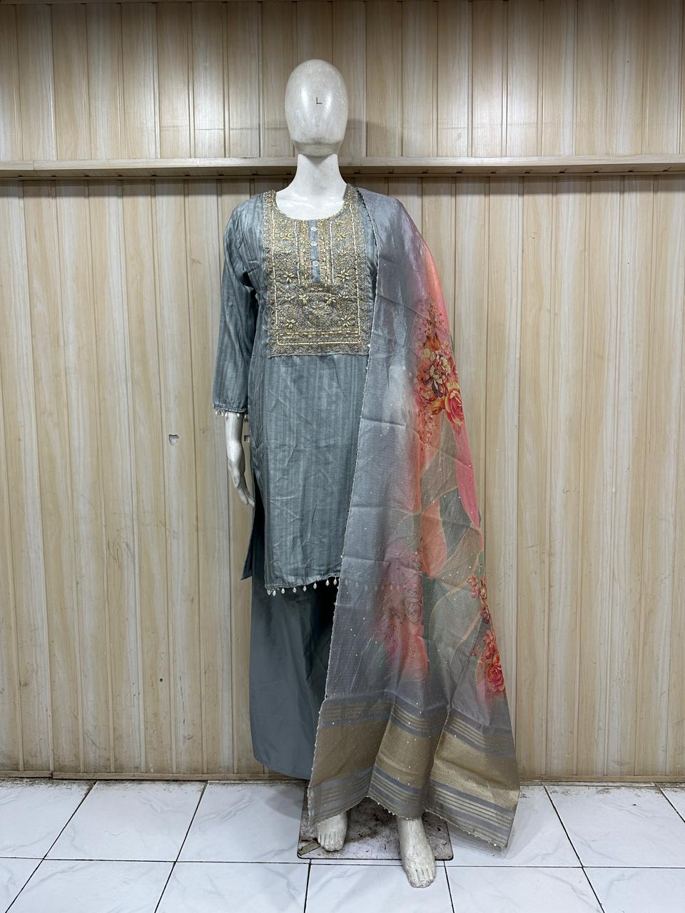 Mannequin wearing a traditional outfit with a gray kurta and floral dupatta against a striped