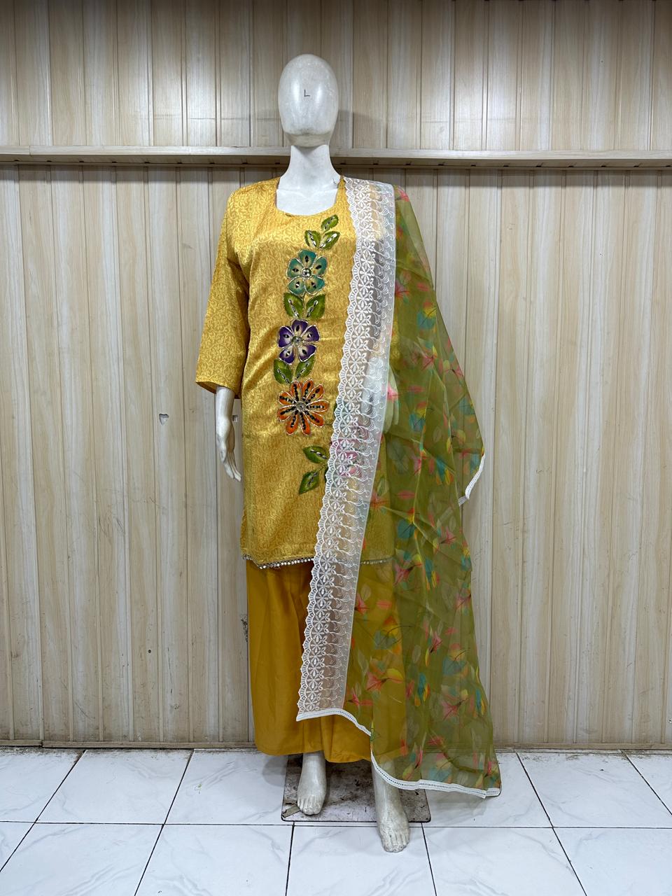 Mannequin wearing a yellow embroidered outfit with a green dupatta against a striped