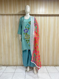 Mannequin wearing a teal outfit with floral embroidery and a red floral dupatta against a wooden panel background.