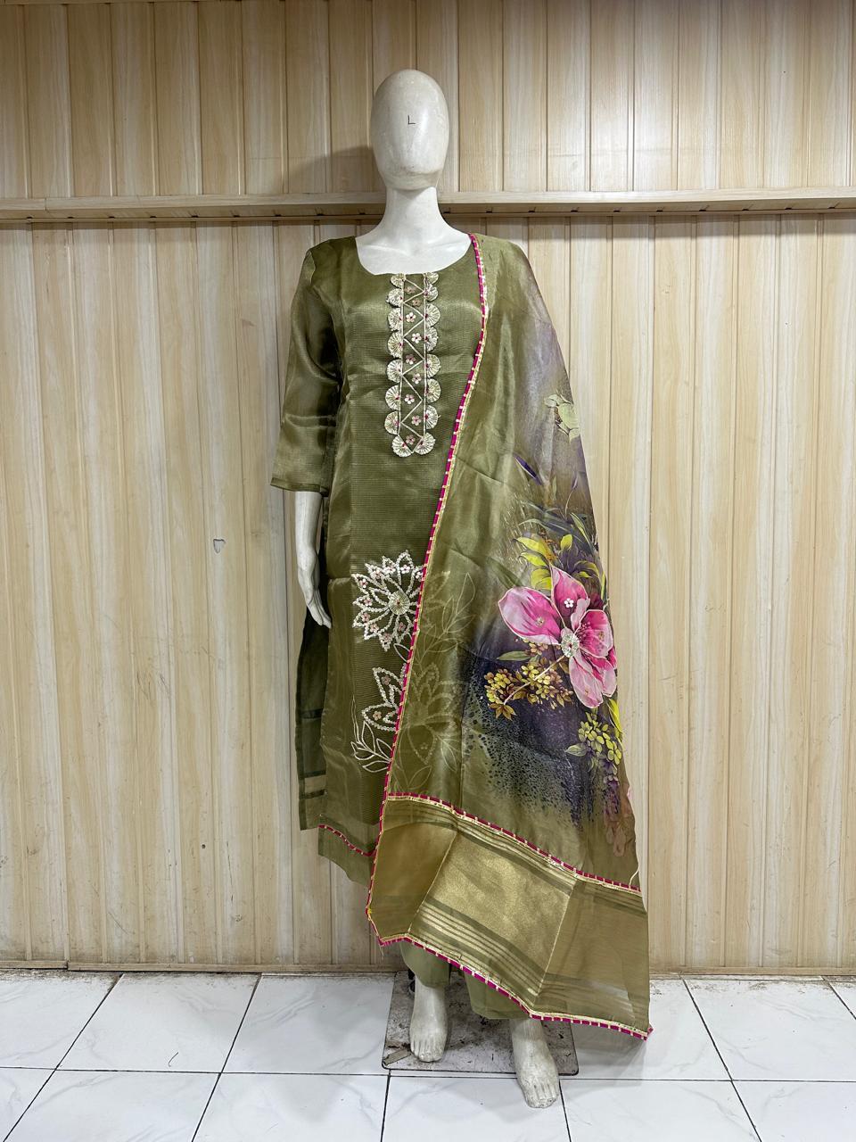 Mannequin wearing a green embroidered dress with a floral dupatta against a striped