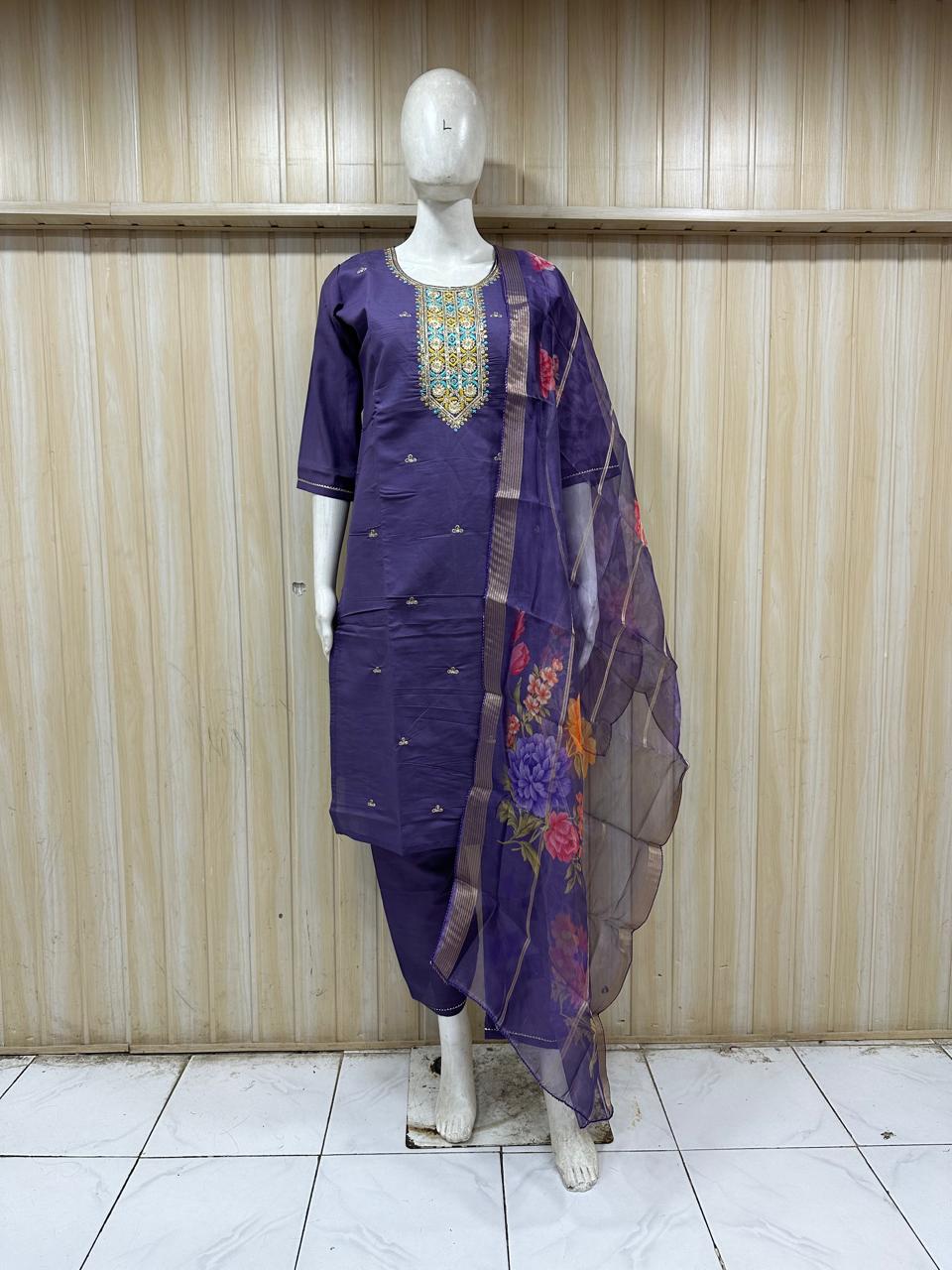 purple embroidered outfit with a floral dupatta on a mannequin against a striped