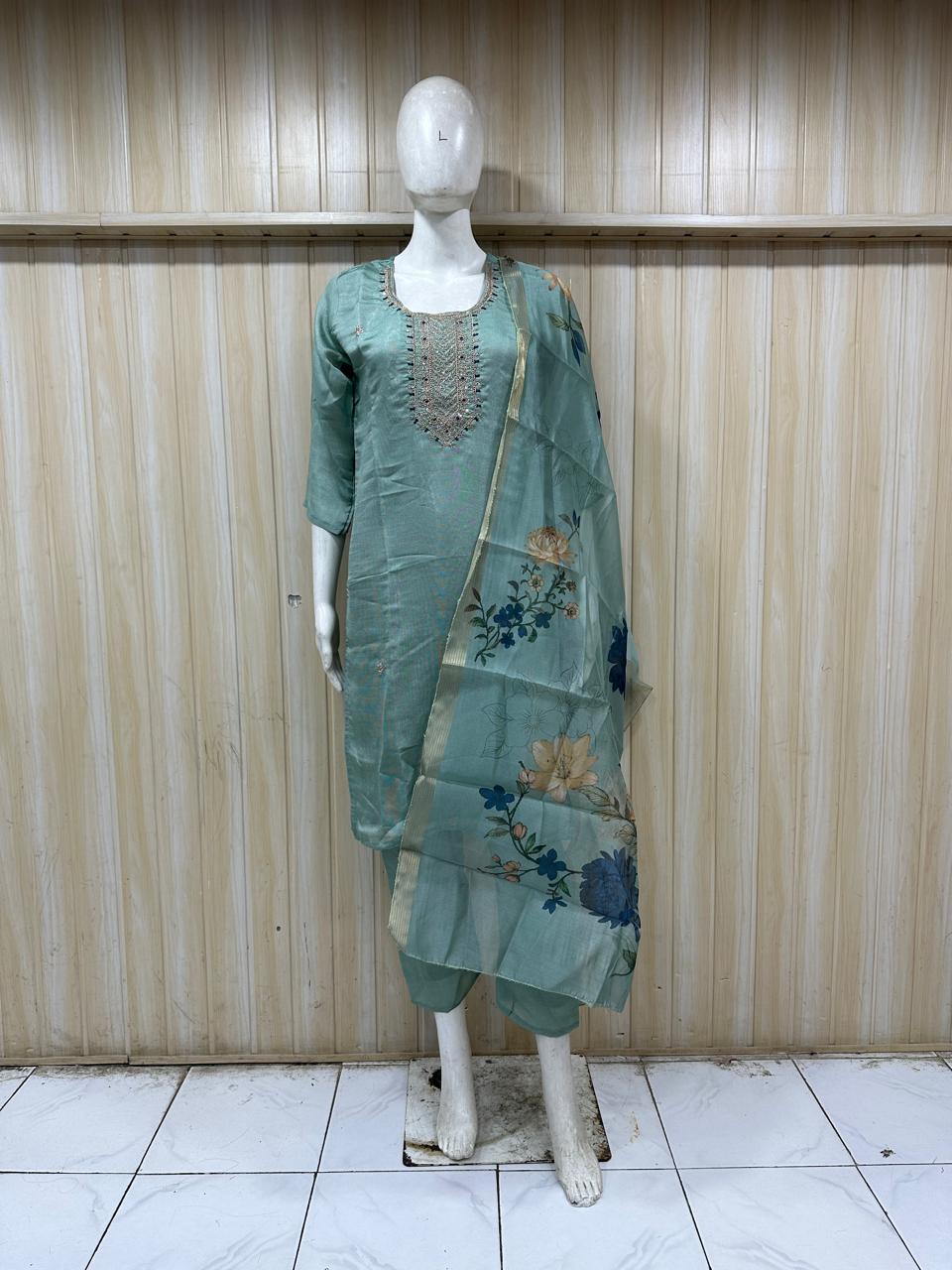 Green traditional outfit with floral patterns on a mannequin against a striped