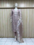 Mannequin wearing a mauve traditional outfit with a long drape against a wooden panel background.