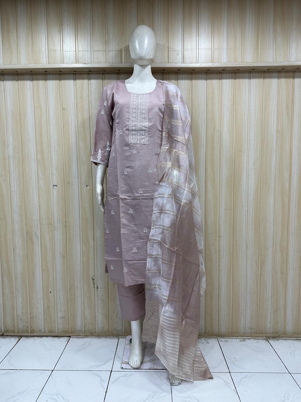 Mannequin wearing a mauve traditional outfit with a long drape against a wooden panel background.