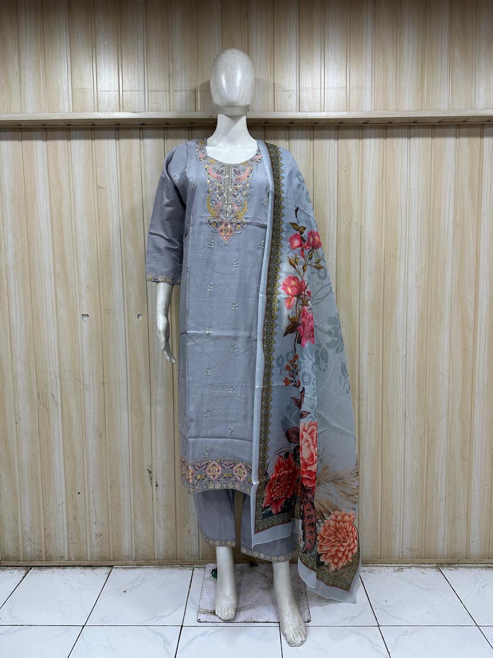 Mannequin wearing a grey traditional outfit with a saree against a wooden panel background