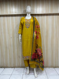 Yellow embroidered outfit with floral dupatta on a mannequin against a striped