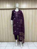 Mannequin wearing a dark purple embroidered outfit against a wooden panel background