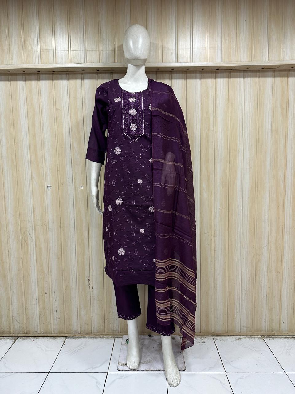 Mannequin wearing a dark purple embroidered outfit against a wooden panel background