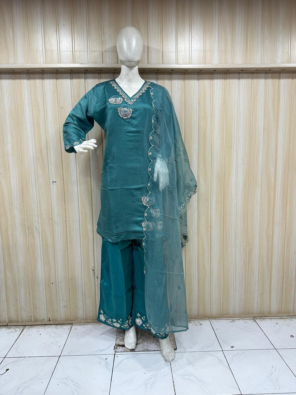 Teal traditional outfit with matching dupatta on a mannequin against a striped
