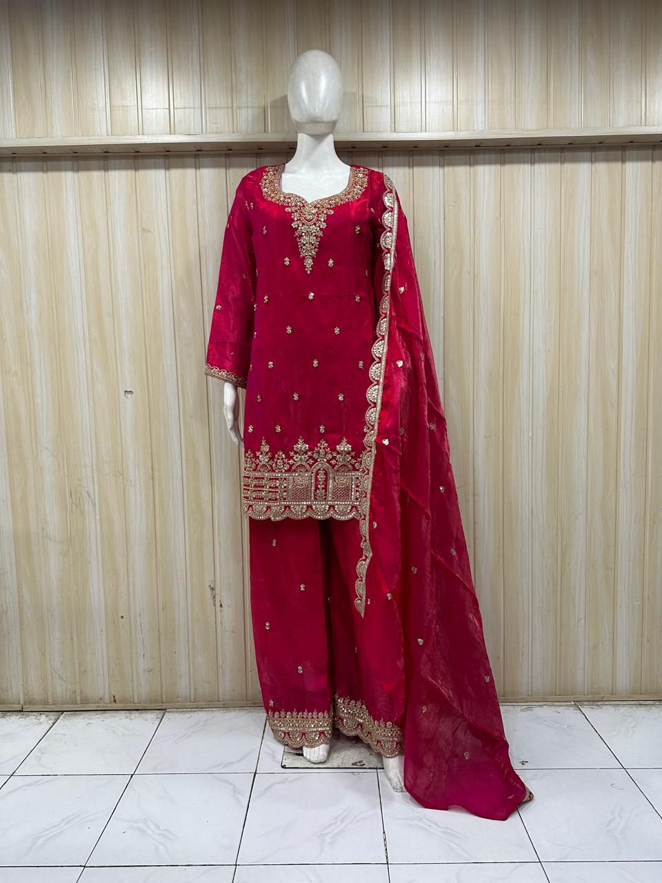 red traditional outfit with gold embroidery on a mannequin against a striped
