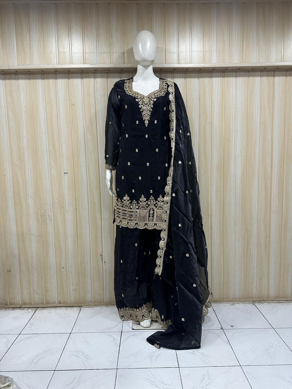 navy blue traditional outfit with gold embroidery on a mannequin against a striped