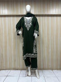 Mannequin wearing a dark green embroidered outfit with a sheer dupatta against a wooden panel background.