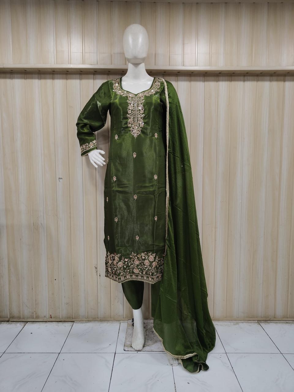 Green embroidered traditional outfit on a mannequin against a striped