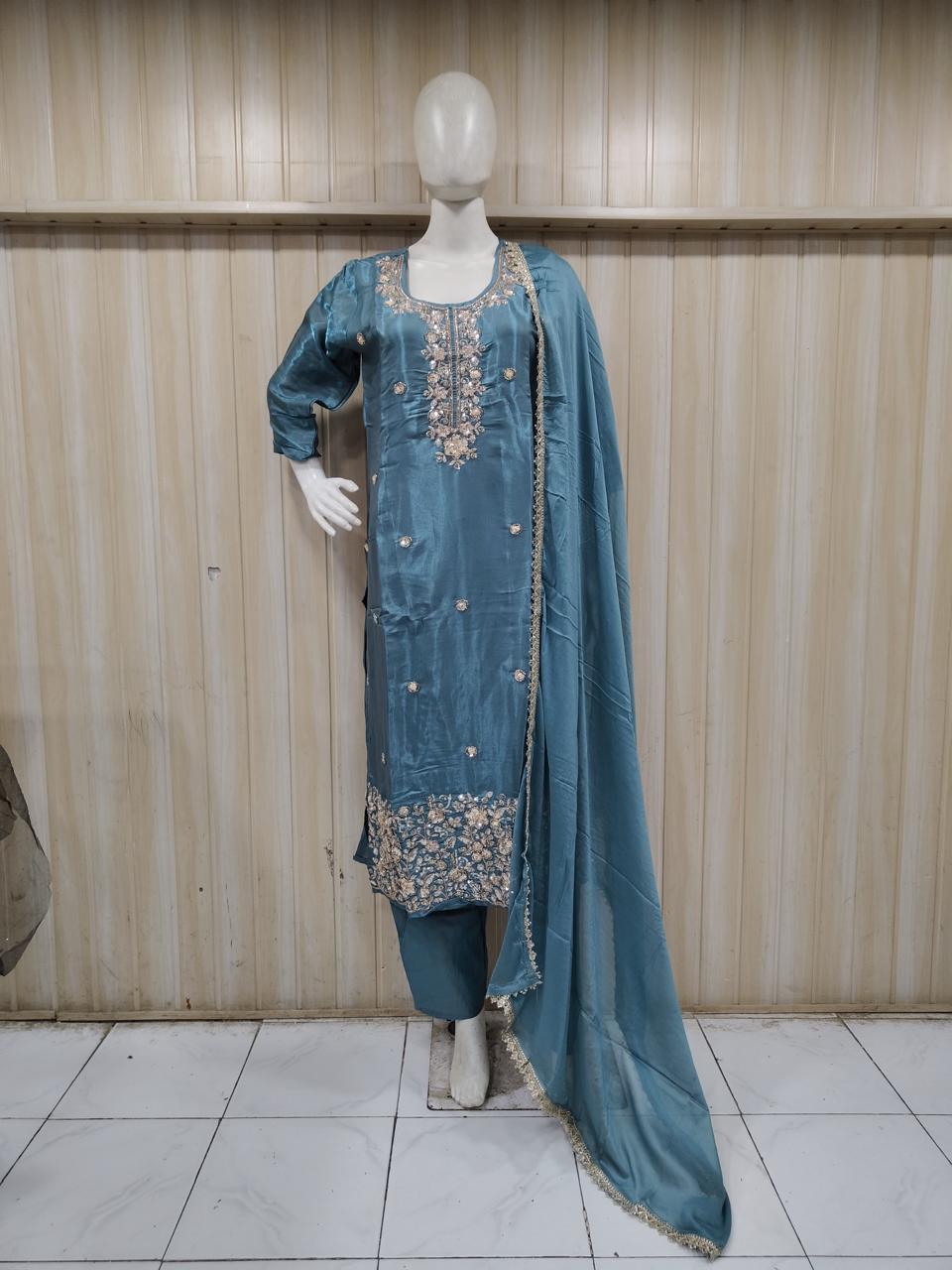 Mannequin wearing a blue embroidered traditional outfit against a striped