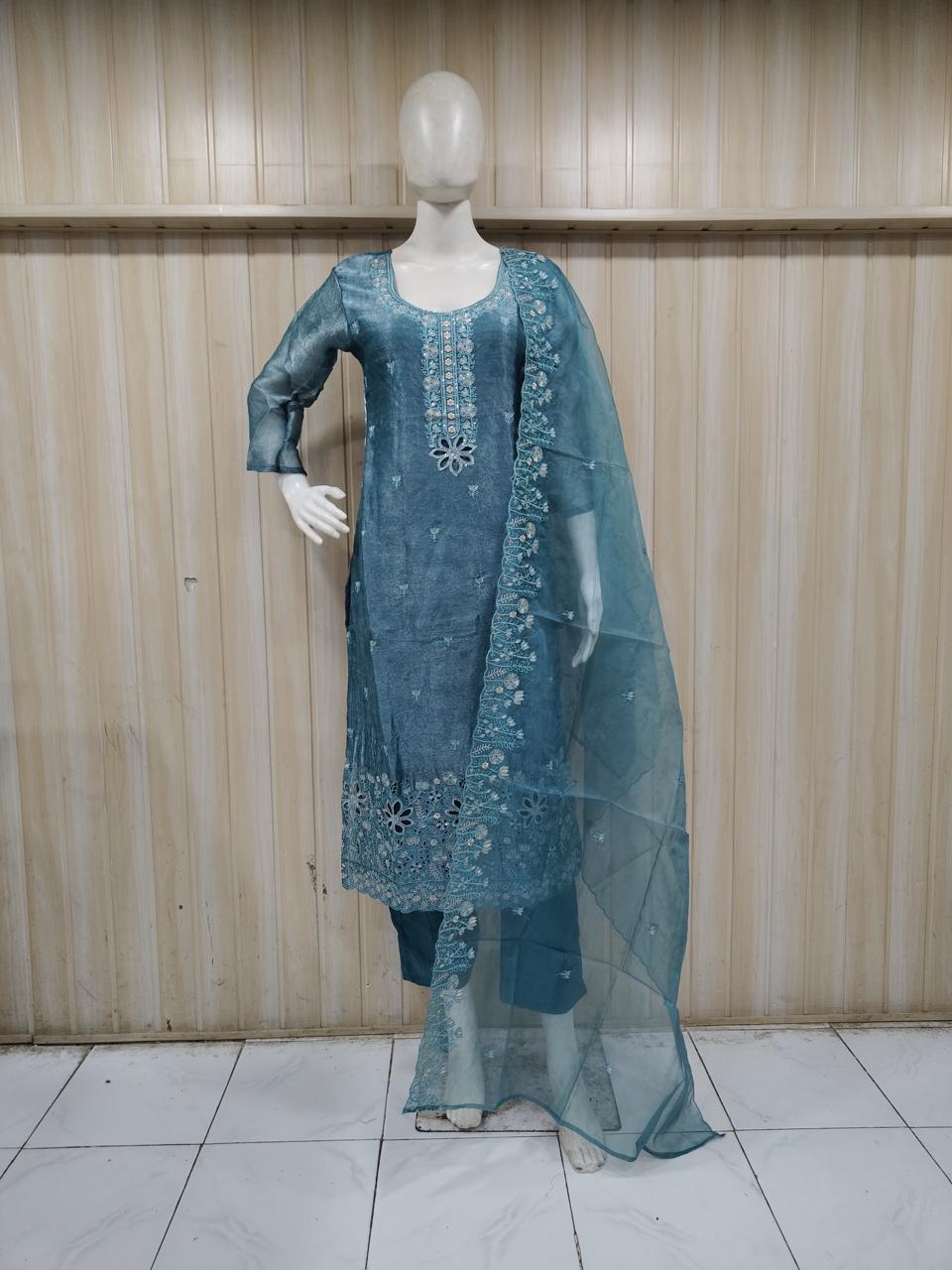 Mannequin wearing a blue embroidered traditional outfit against a striped