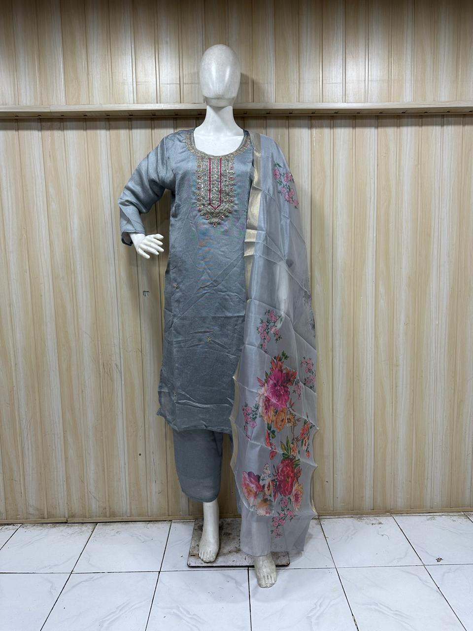 Mannequin wearing a grey embroidered outfit against a striped