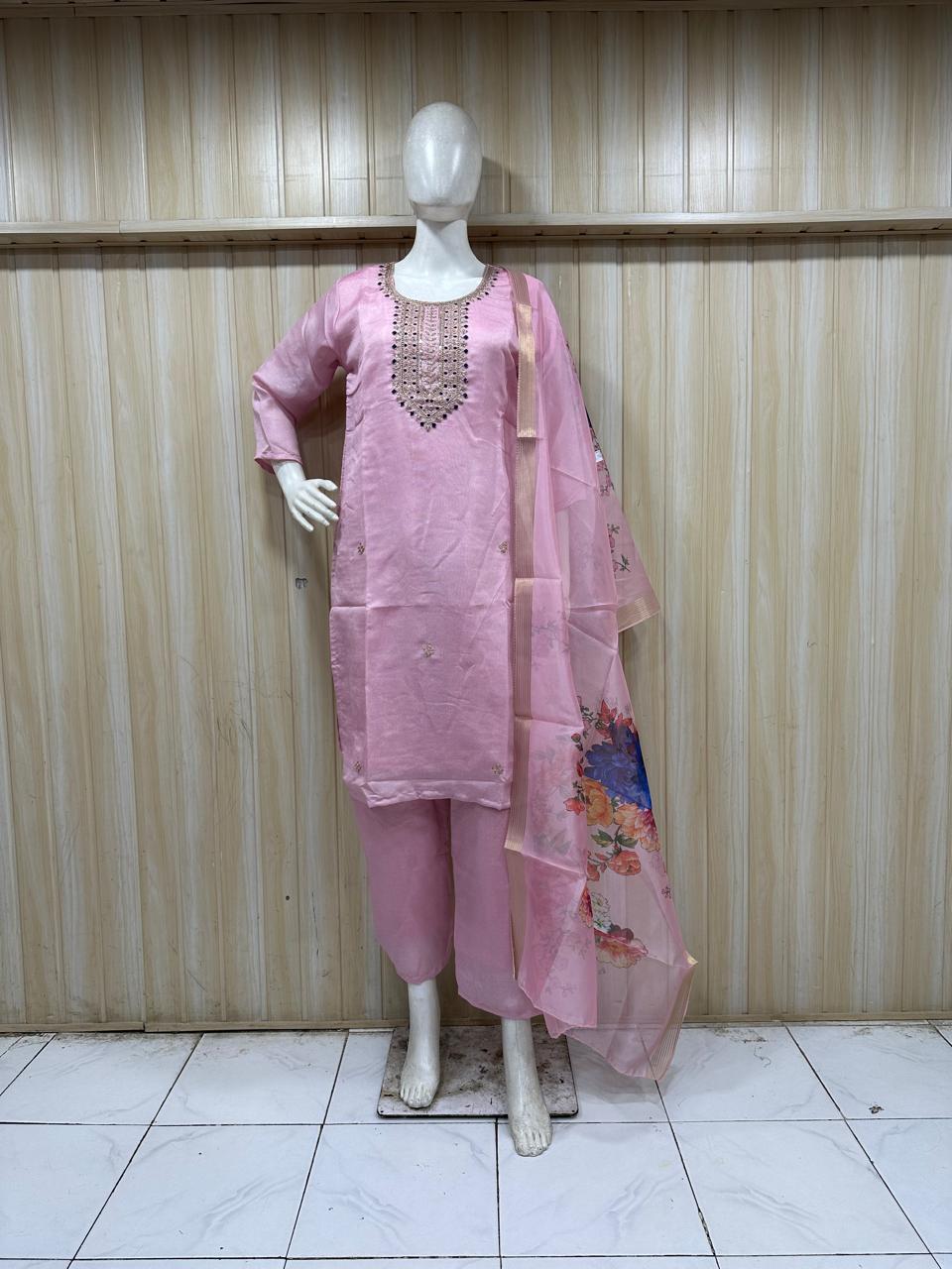 Mannequin wearing a pink embroidered outfit against a striped