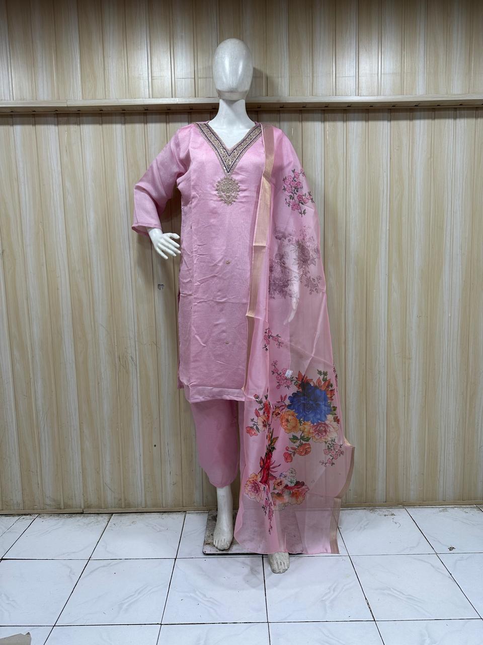 Mannequin wearing a pink traditional outfit with a floral dupatta against a striped