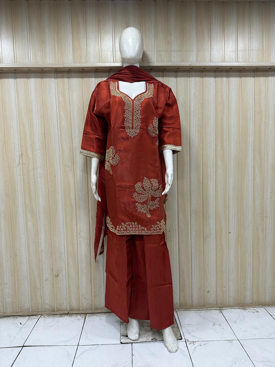 Elegant red traditional outfit with floral dupatta on mannequin against striped background – perfect for a bold, festive & classy ethnic look