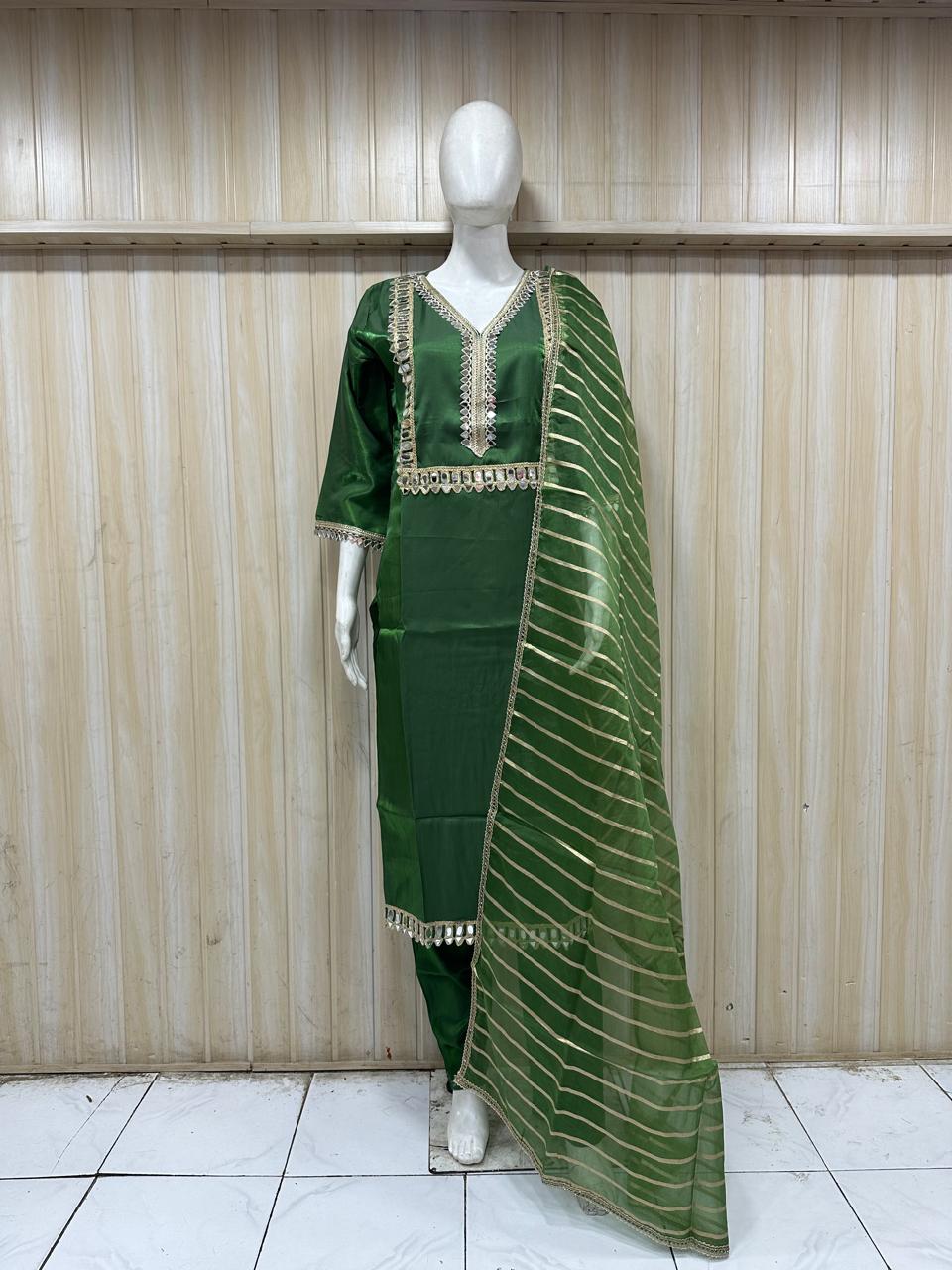 Mannequin wearing a green traditional outfit with a floral dupatta against a striped