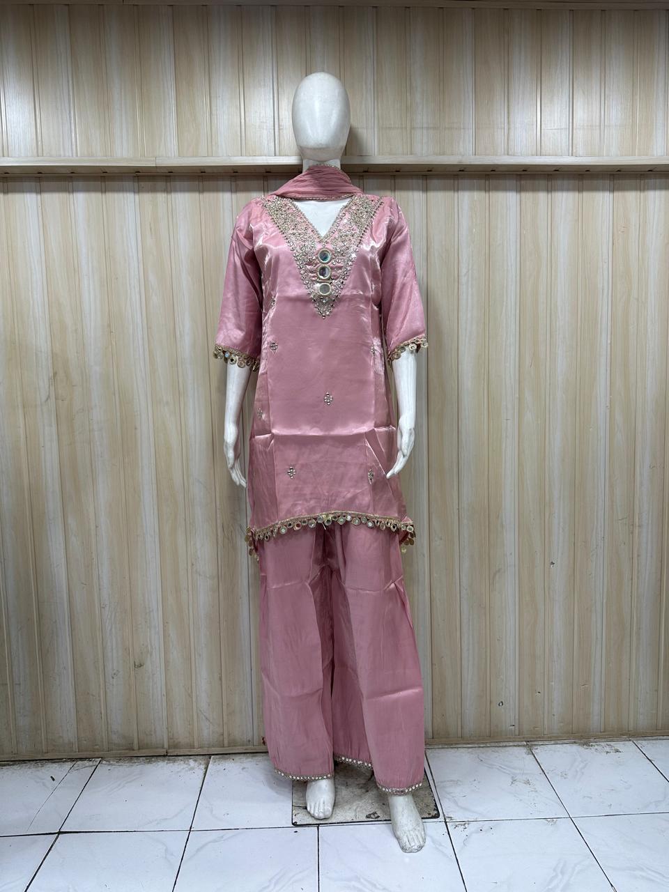 pink embroidered dress with a matching dupatta on a mannequin against a striped