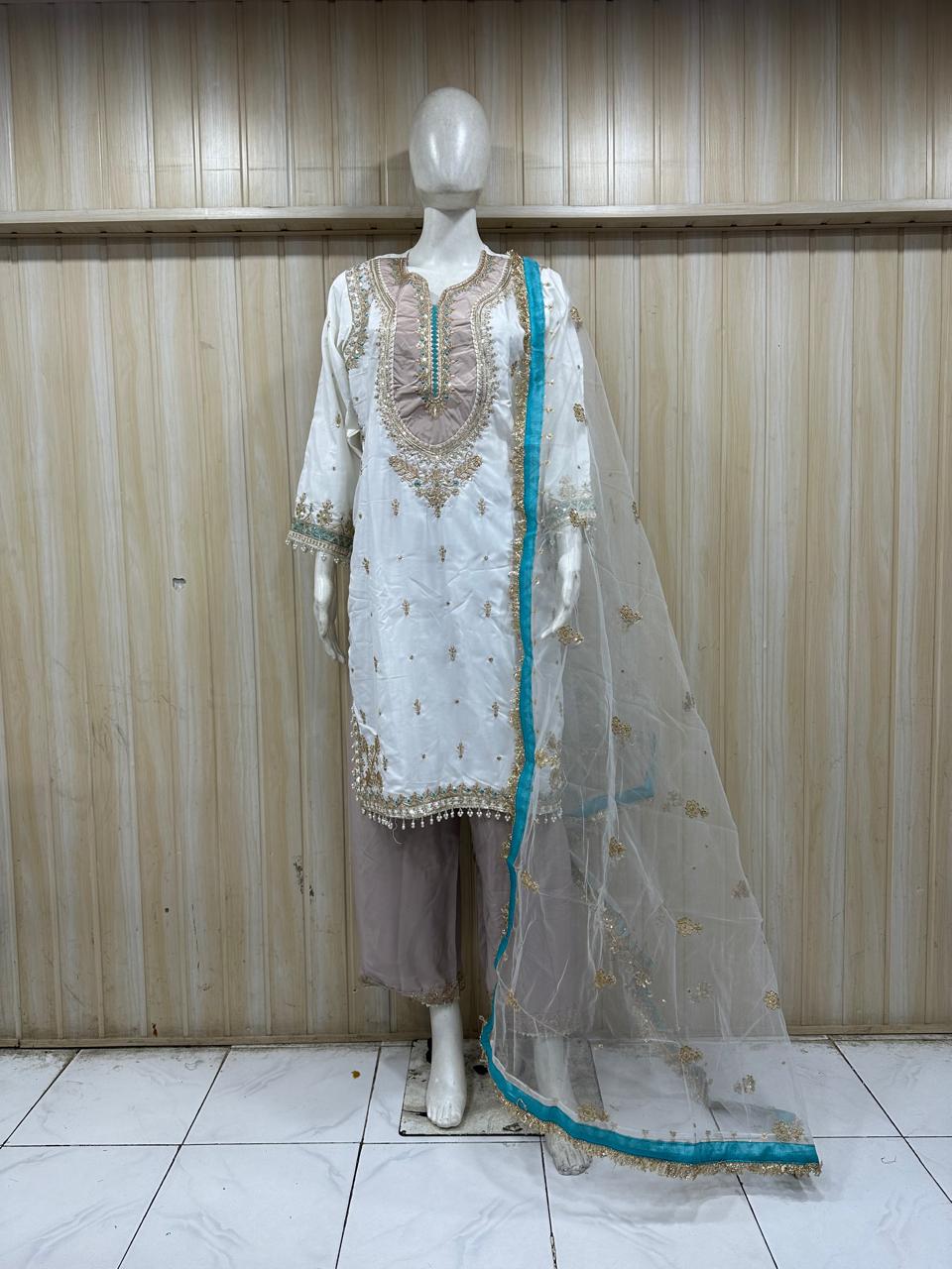 white and grey embroidered dress with a matching dupatta on a mannequin against a striped